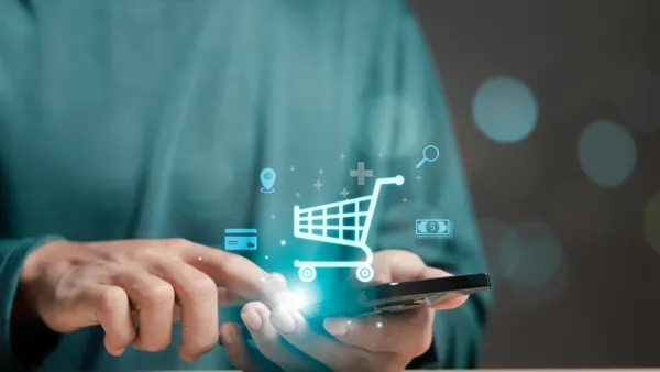 Man holding a smartphone displaying a shopping icon on the screen, indicating online shopping activity.