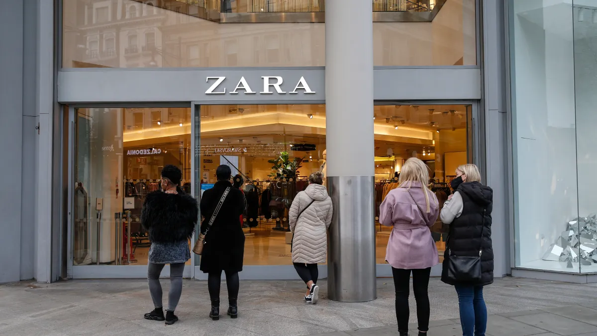 Shoppers walk in front of a Zara storefront.