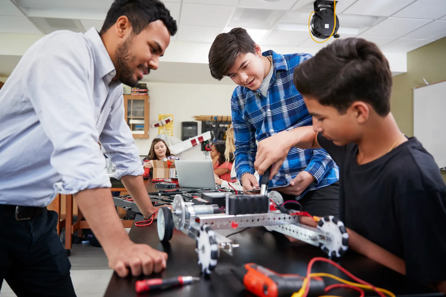 Teacher instructing students as they build a robotic vehicle in a science lesson.