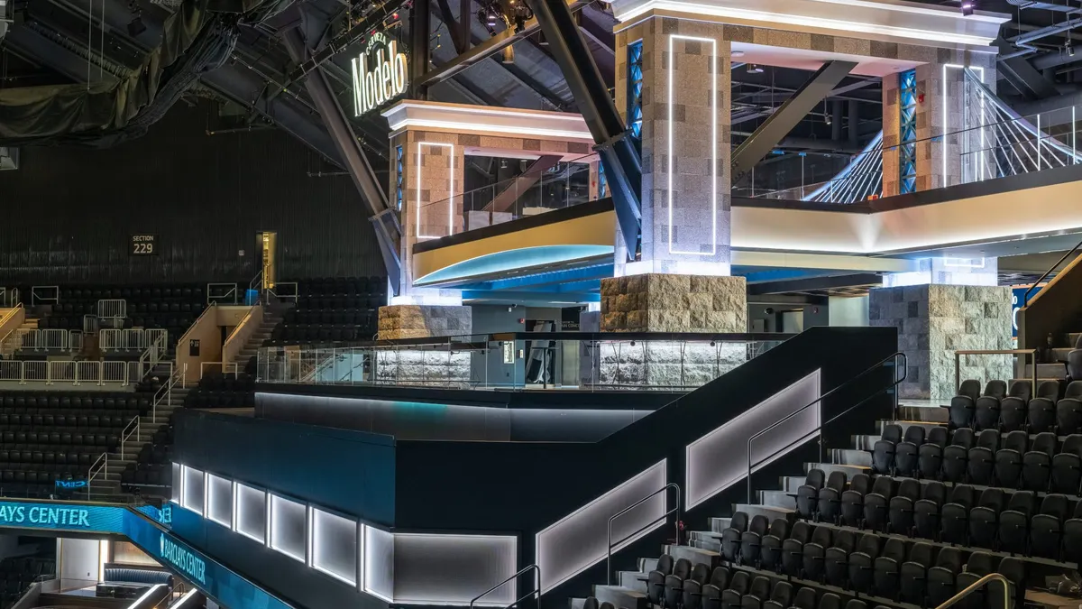 A picture of a fancy interior with stadium seating. On a highrise, a large mock-up of an arched bridge looms.