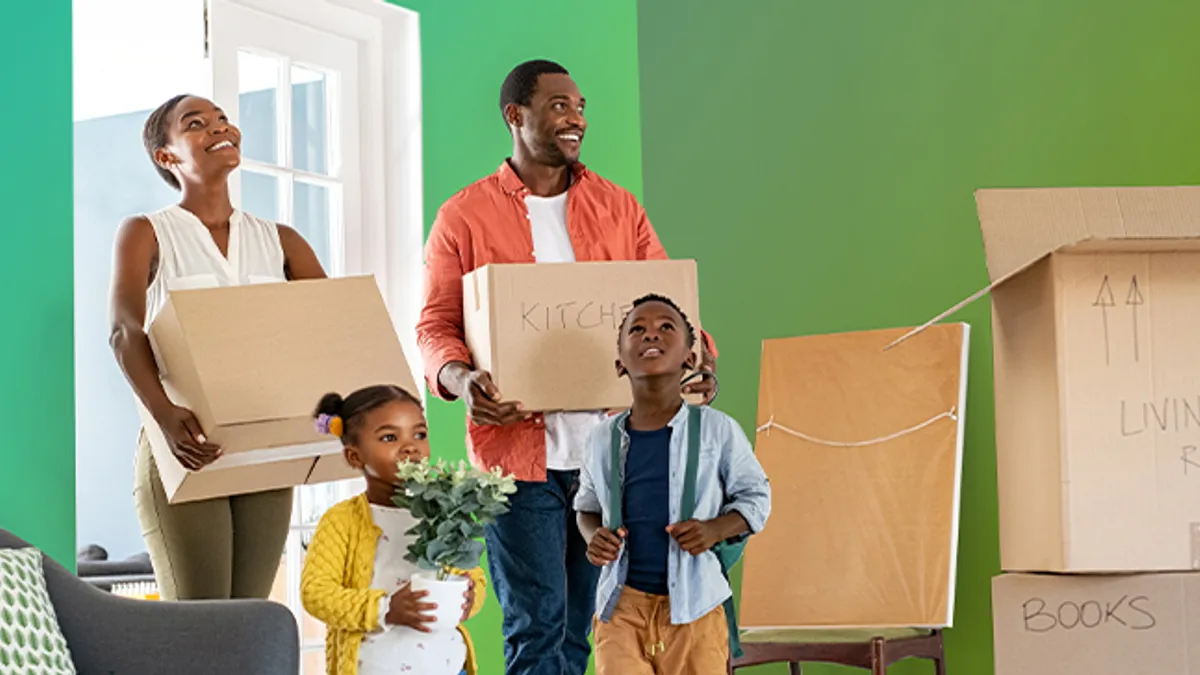 A family of four carrying boxes and moving into a new home