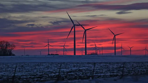 The sun sets behind wind turbines