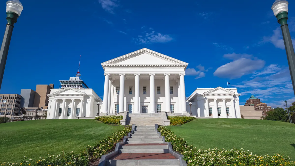 A white building on a green field with multiple columns at the front.