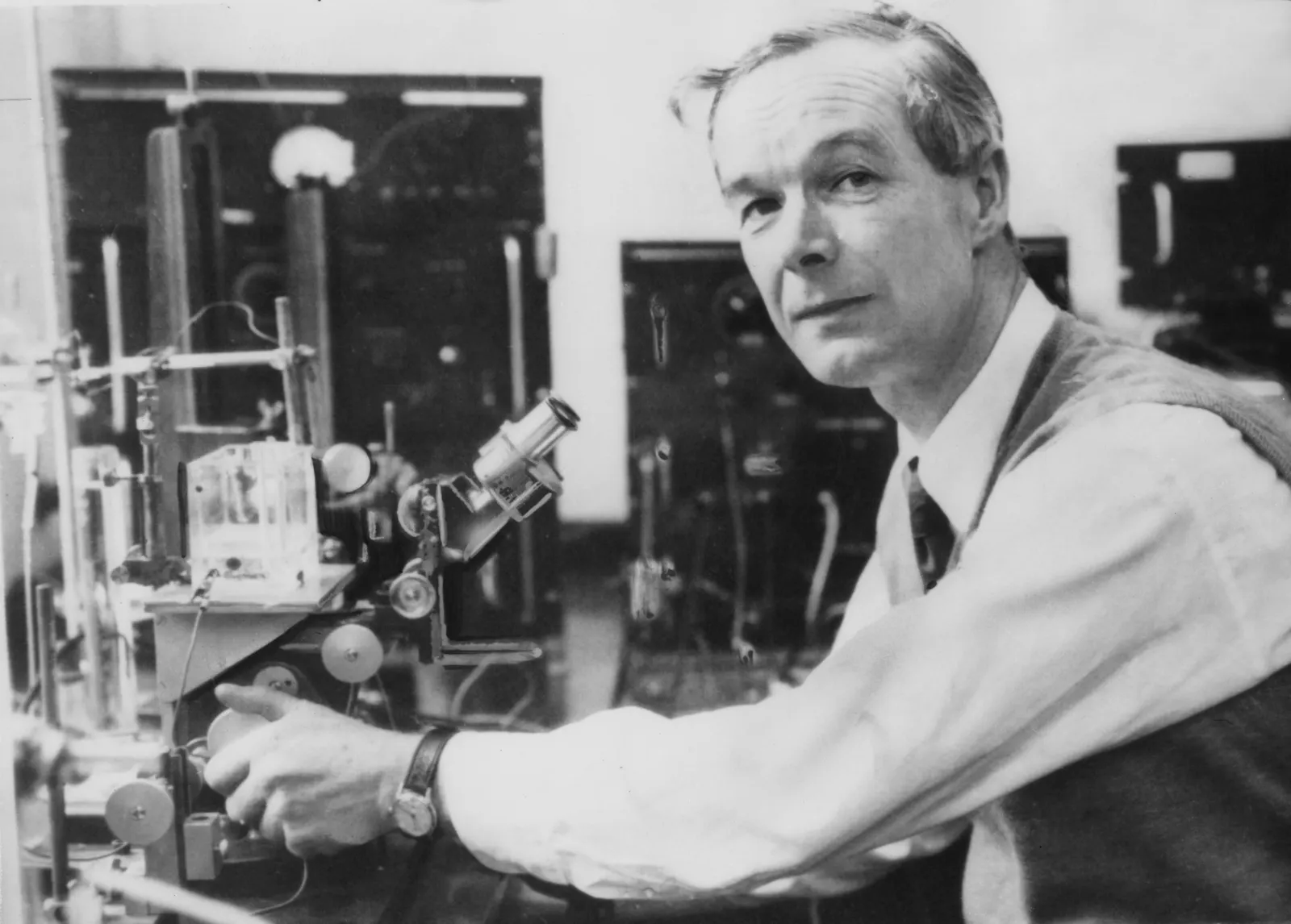A man turns a dial on a microscope in a research laboratory.