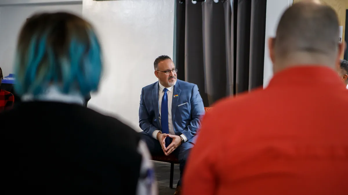 Miguel Cardona sits in front of an audience