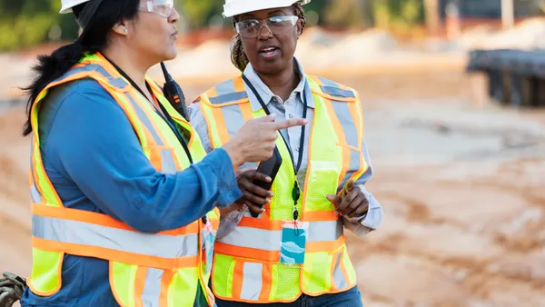 Two women construction workers discuss a project.