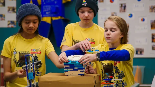 Three students work on a robotics project in a room