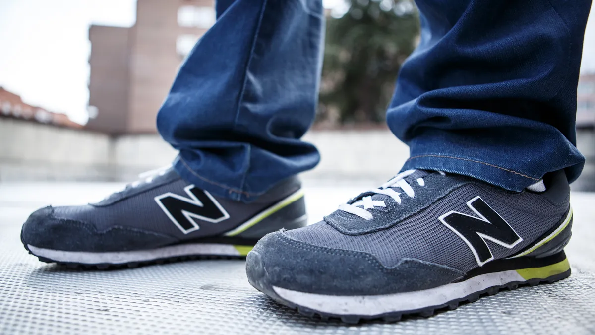 A person wears a pair of gray New Balance sneakers and jeans.