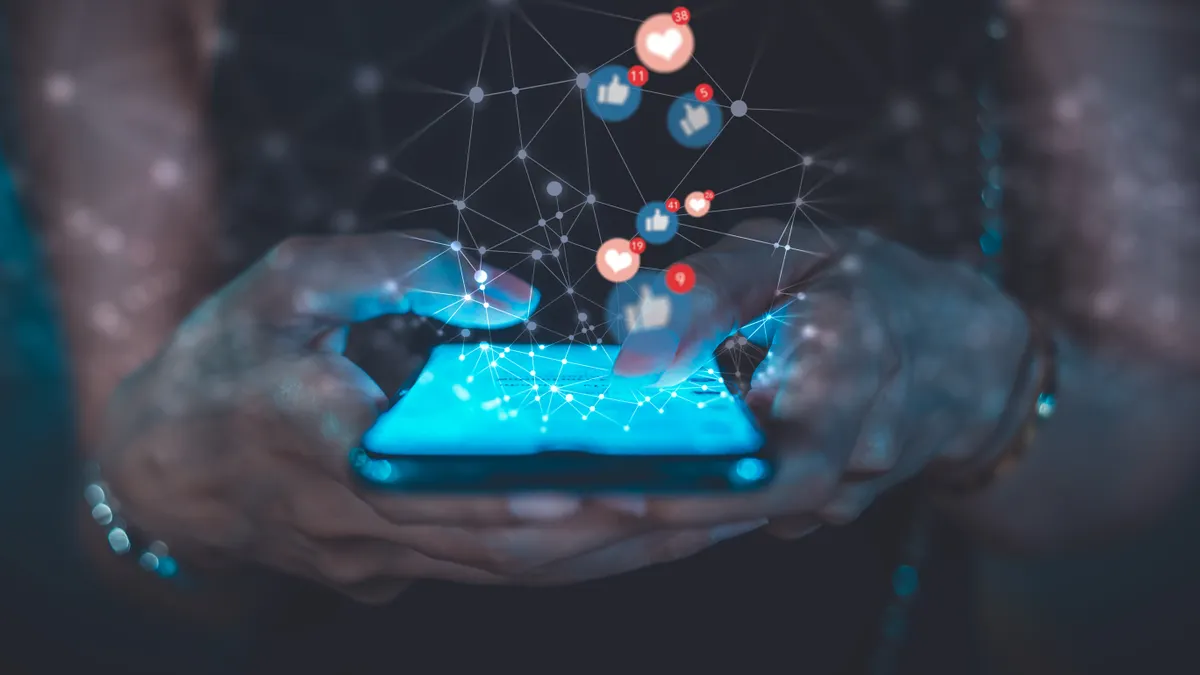Close up image of a person's hands texting on the phone in the dark with social media like and heart buttons floating out of the phone screen