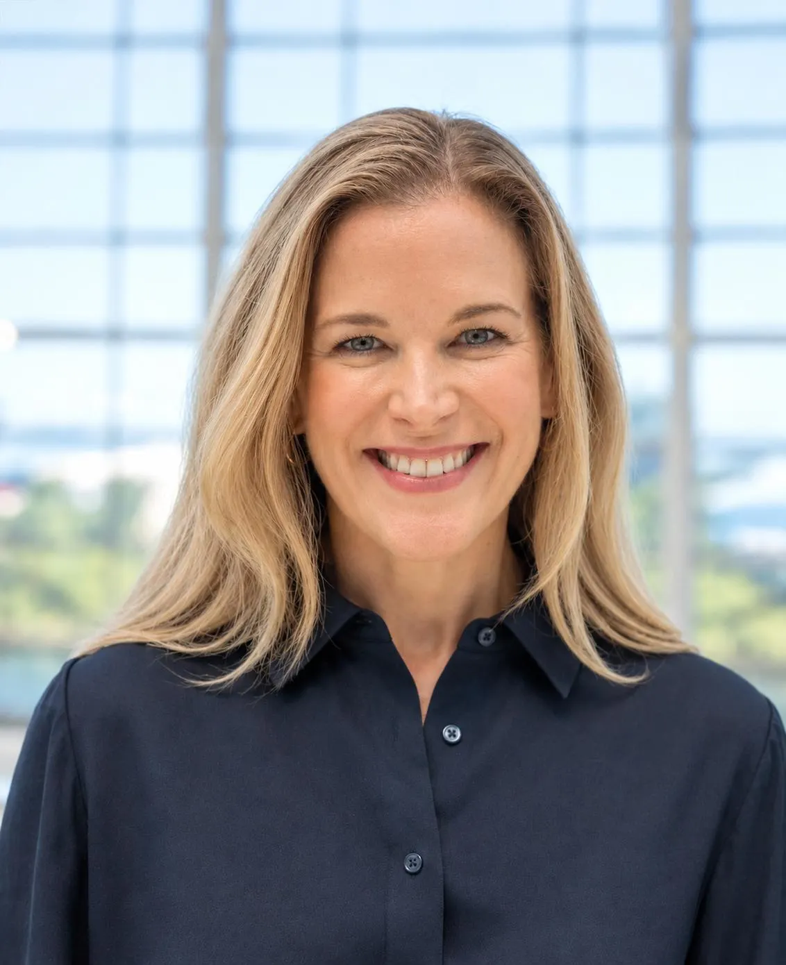 An image of a person smiling. The person is wearing a navy blue button-downed shirt