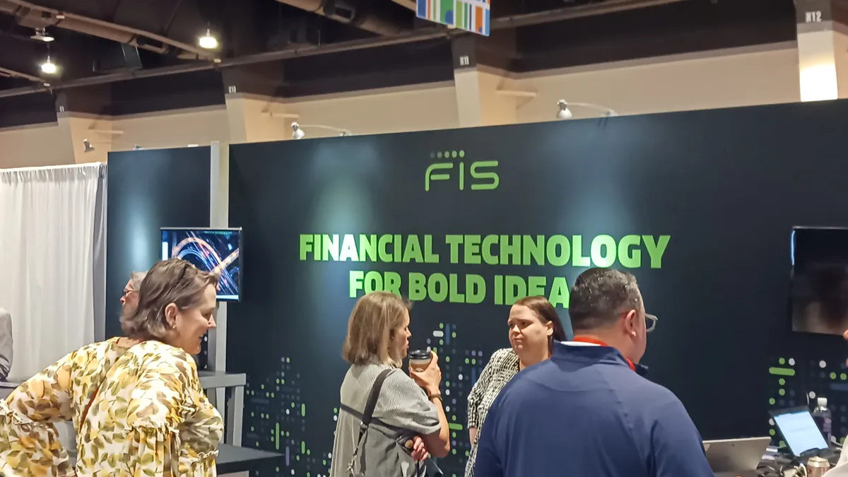 People standing at a booth in front of a conference booth with a placard that says 'FIS.'