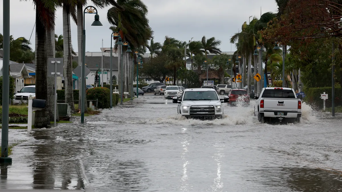 Vehicles drive through a flooded street after Hurricane Nicole came ashore on November 10, 2022 in Fort Pierce, Florida.