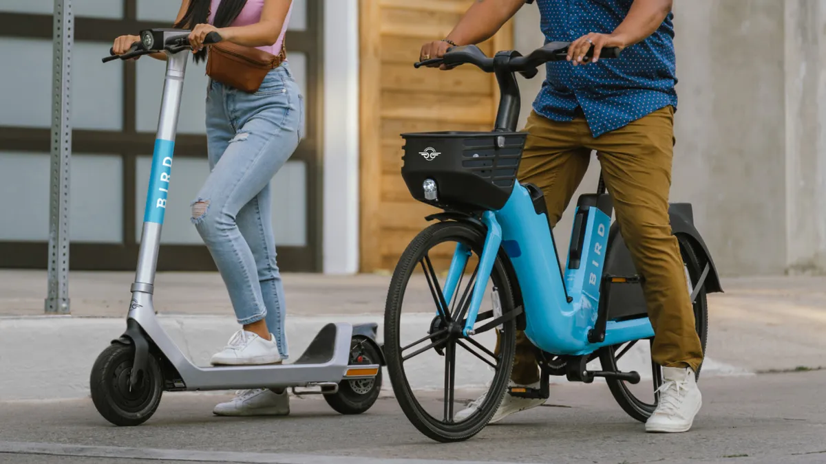 Two people using a Bird bike and a Bird scooter.