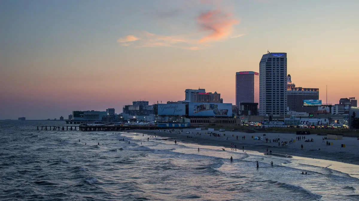 Sunset in Atlantic City. Shows the ocean, a pier, and casinos at sunset.