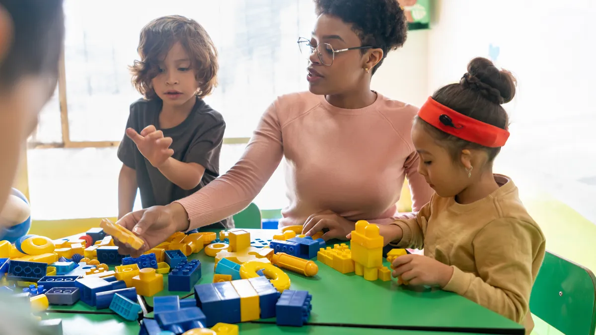 African American teacher playing with toy blocks in class at the school.