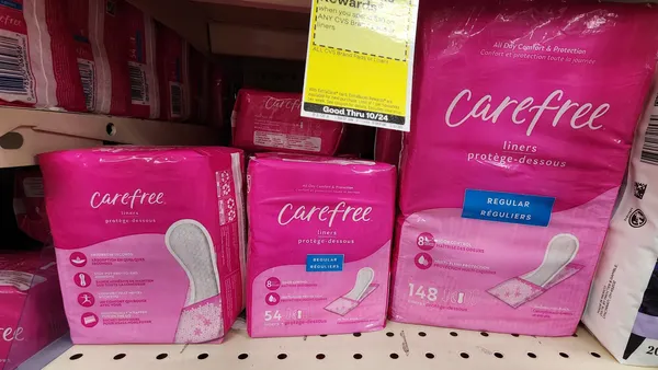Three squared hot pink packages standing side-by-side in a row on a shelf.