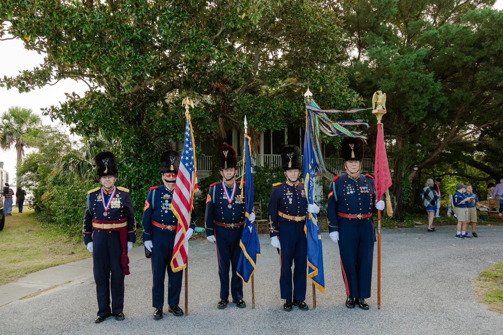 People wearing blue uniforms and holding flags stand in a line.