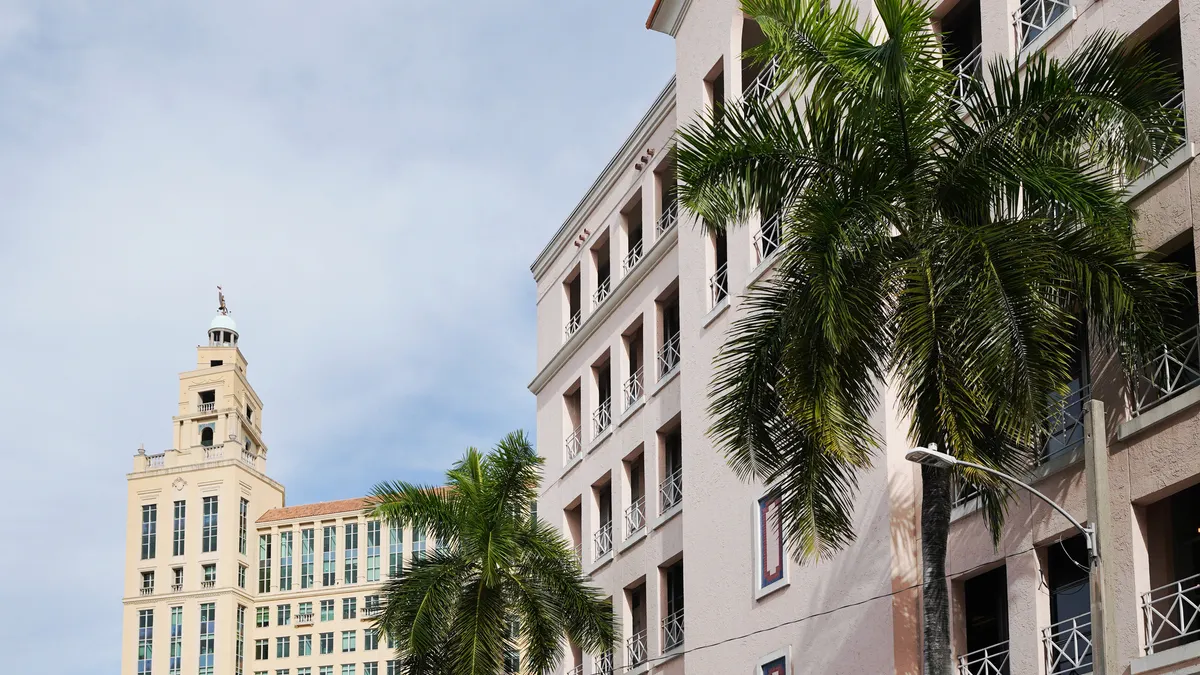 View of downtown Coral Gables, Florida shows beige buildings and palm trees