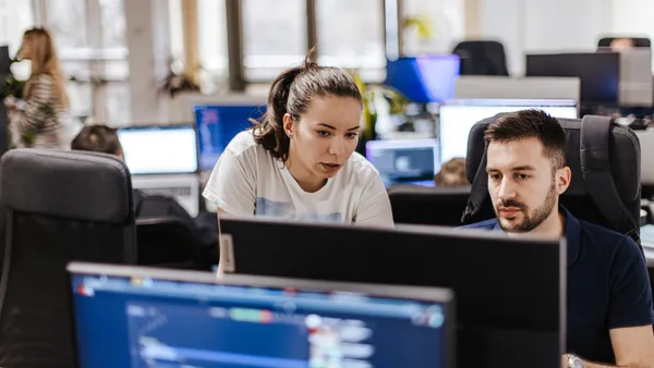 two technology workers look at a screen in an office setting