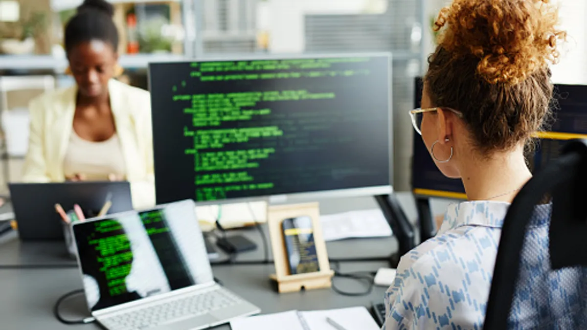 Woman coding with multiple monitors