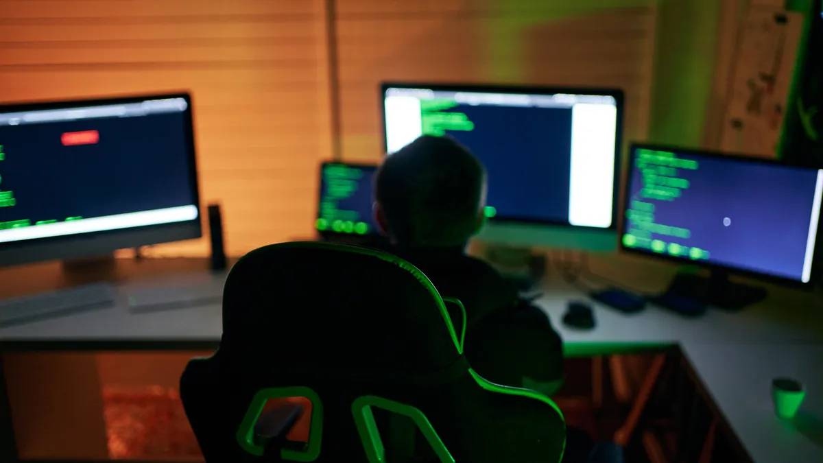 Young male hacker sitting in a room, working on his computer