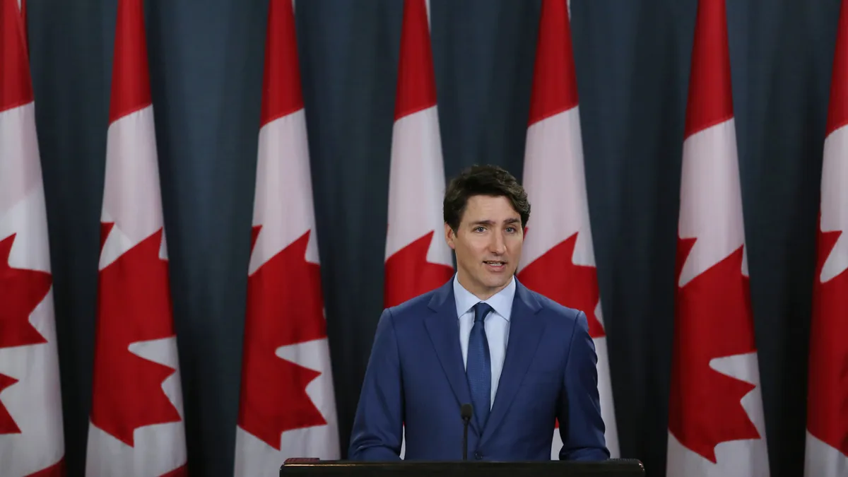 A person standing in front of the Canadian flag.