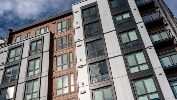 A modern, mid-rise apartment building with a wood and white panel facade.