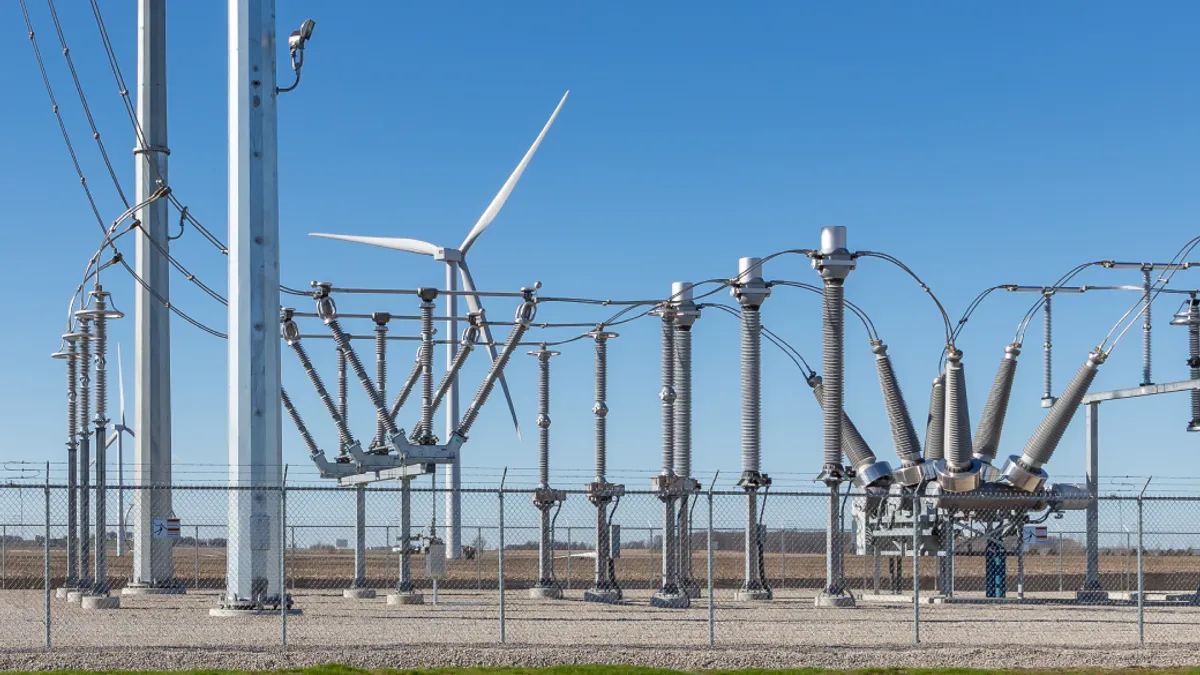 electrical substation with a wind turbine in background supplying the power