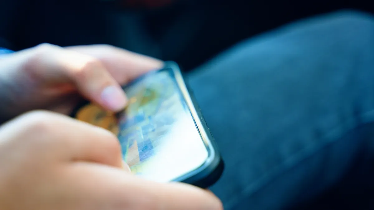 A photo of a person holding a mobile phone horizontally and playing a game on the phone.