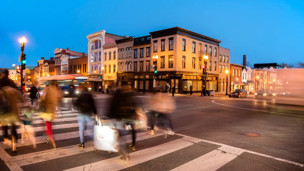 People cross a busy intersection at night.