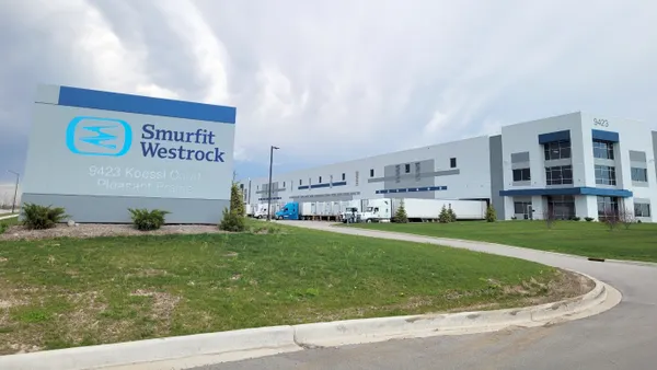 The exterior of an industrial facility with a sign next to a driveway that has Smurfit Westrock's logo.