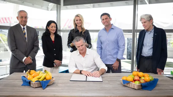 Gov. Gavin Newsom signs a bill next to baskets of fruit