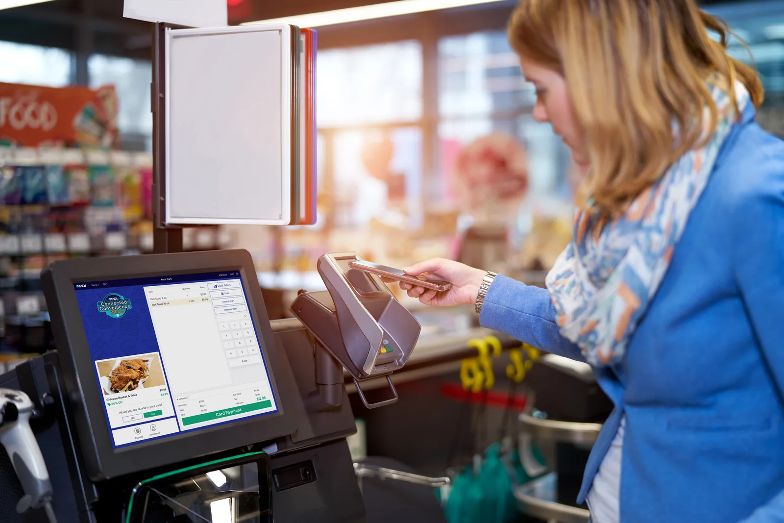 A photo of a person using their phone to pay for purchases at a self-checkout kiosk.