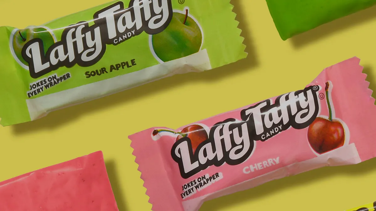 Three pieces of Laffy Taffy in different colors and flavors: yellow for banana, pink for cherry and purple for grape.
