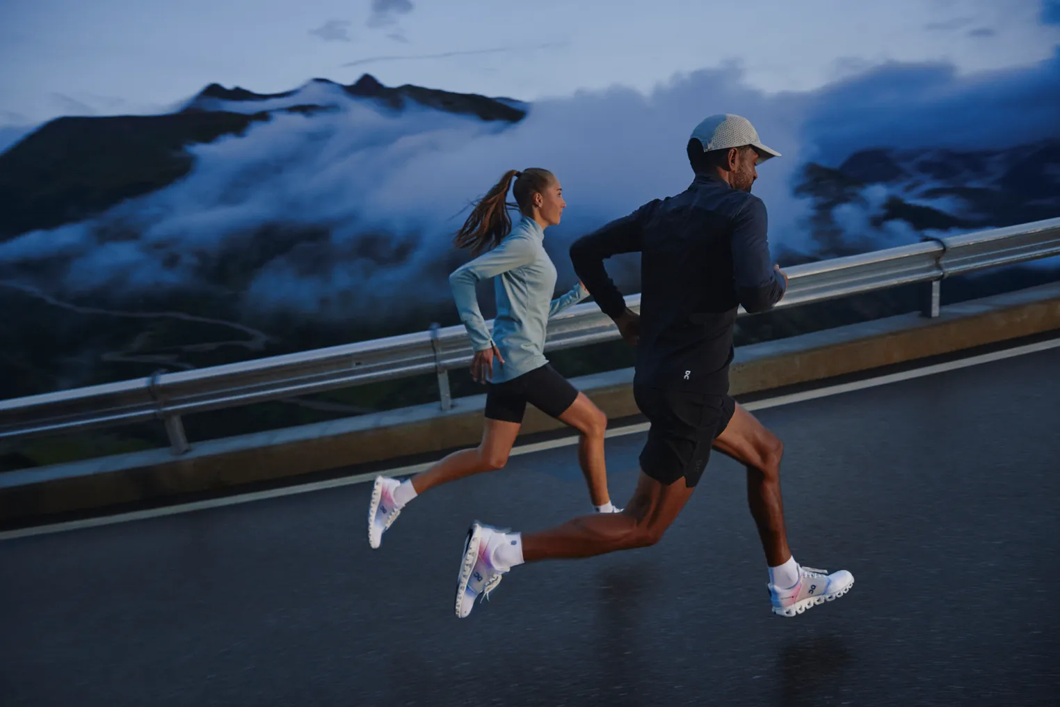 Two runners in long sleeves on a road with clouds in the sky