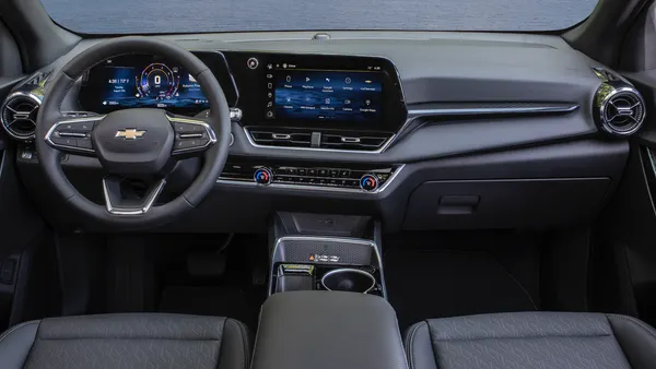 An interior view of the dashboard of a 2025 Chevrolet Equinox LT SUV parked outdoors overlooking a body of water.