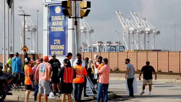 A group of dockworkers gather outside an ocean terminal.