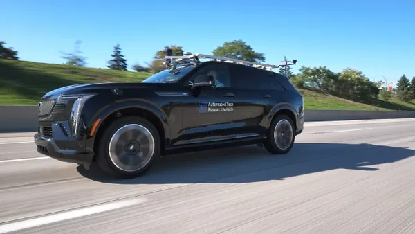 A GM-operated automated research SUV tests autonomous-driving technology on a highway with blue sky in the background.