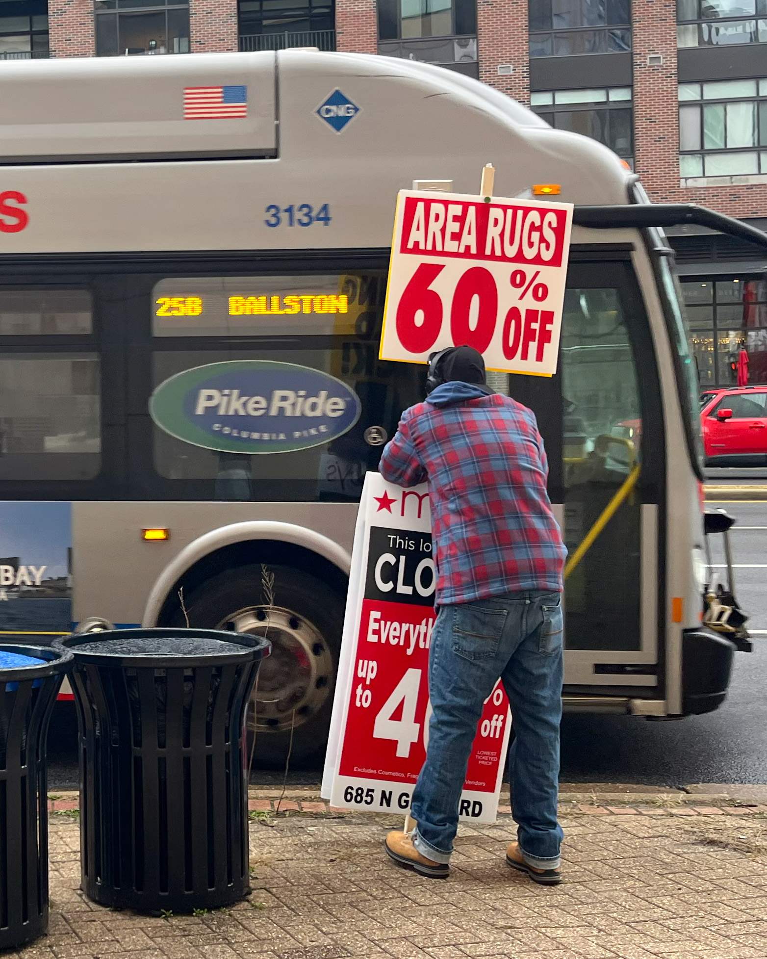 A person stands with a sign advertising Macy&amp;#x27;s store closing sales.