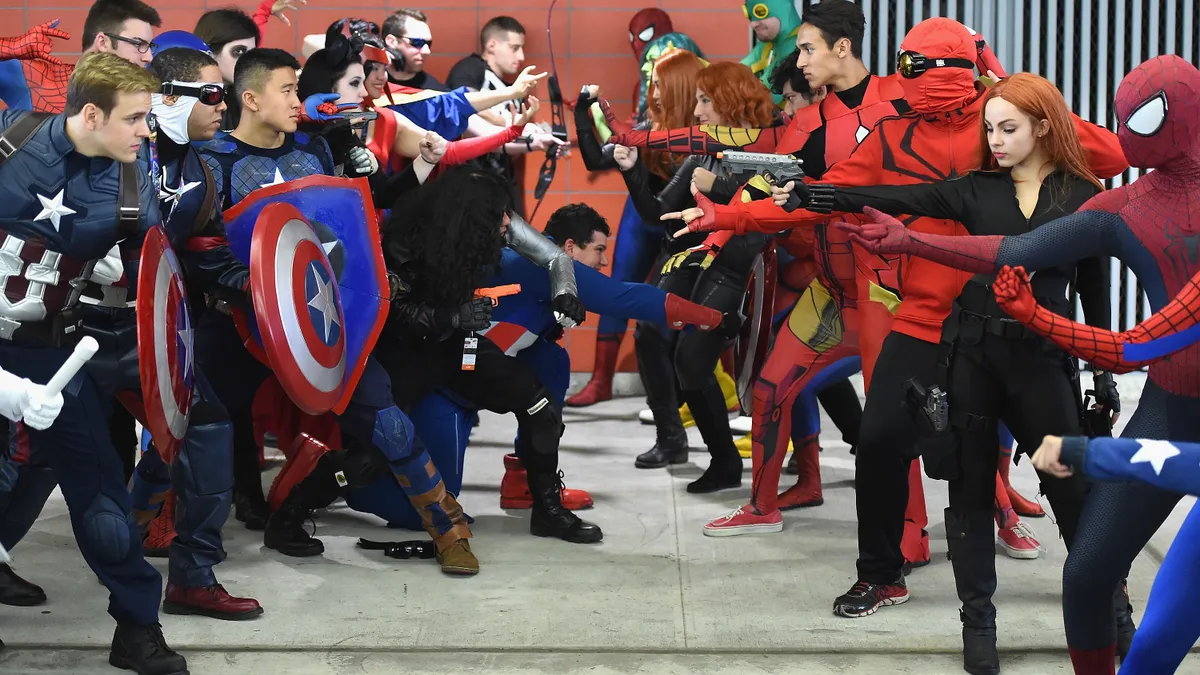 A group of people dress up as superheroes outside a comic convention.