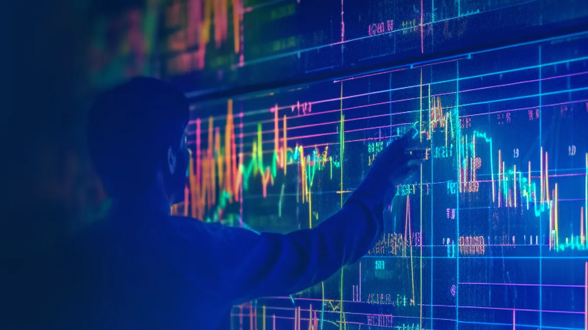 Person pointing at line chart on a large screen.