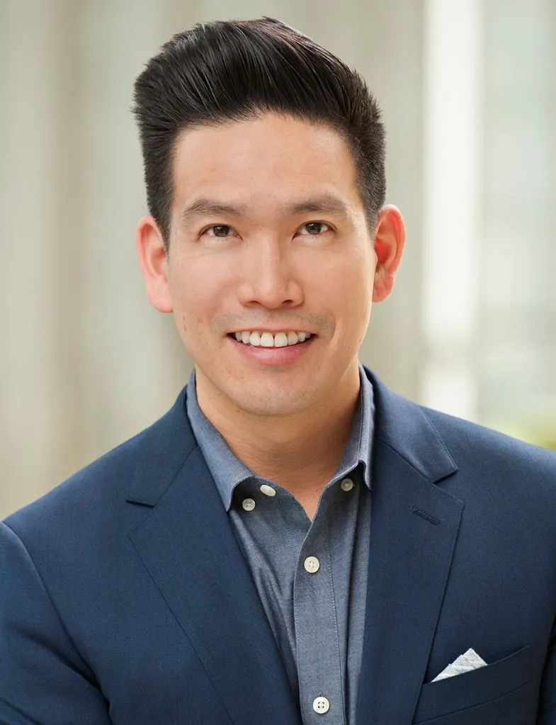 An image of a man with a suit smiling.