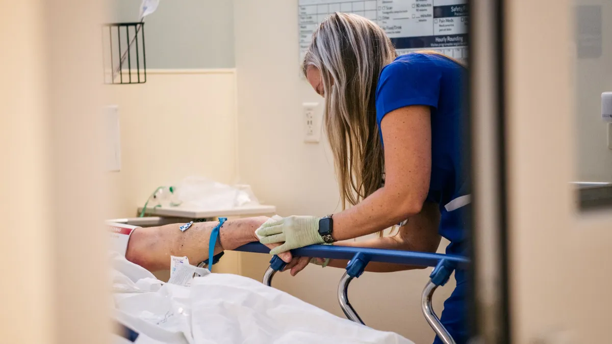 A nurse is seen caring for a patient just out of view.