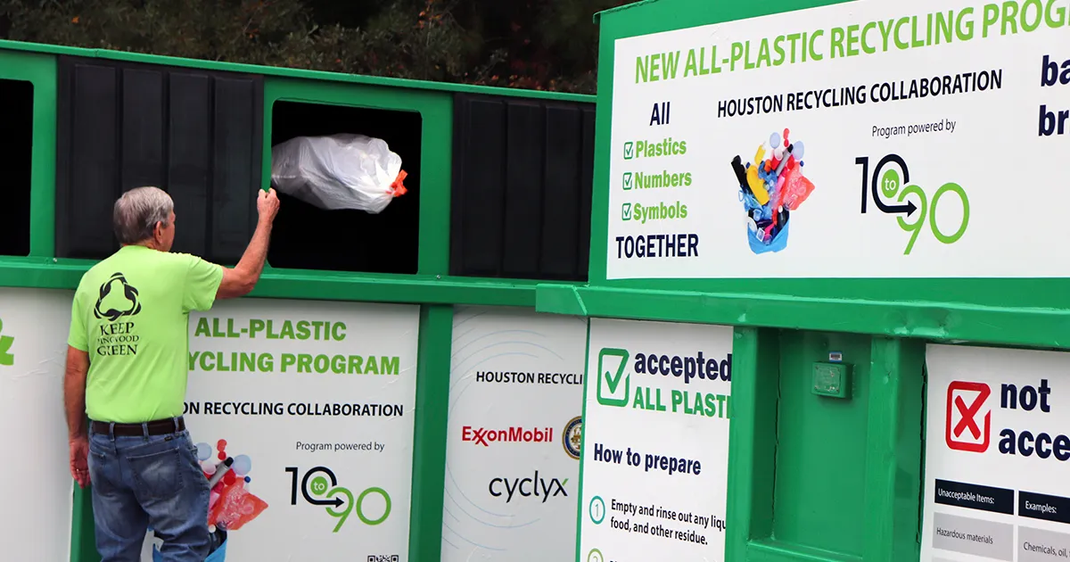 A person throws a bag of recyclables into a bin run by the Houston Recycling Collaboration