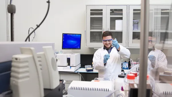 A Cleveland Diagnostics lab technician wearing a white coat and blue gloves analyzes results from an IsoPSA sample in a lab.
