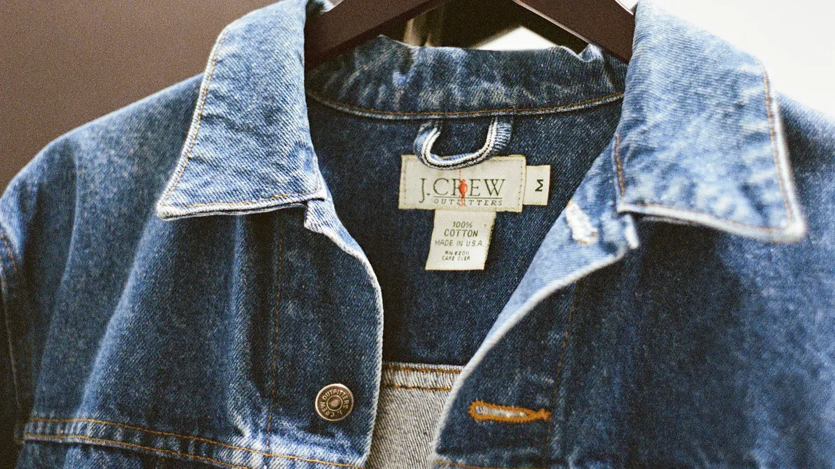 A close-up of the collar and inside tag of a somewhat faded denim jacket.