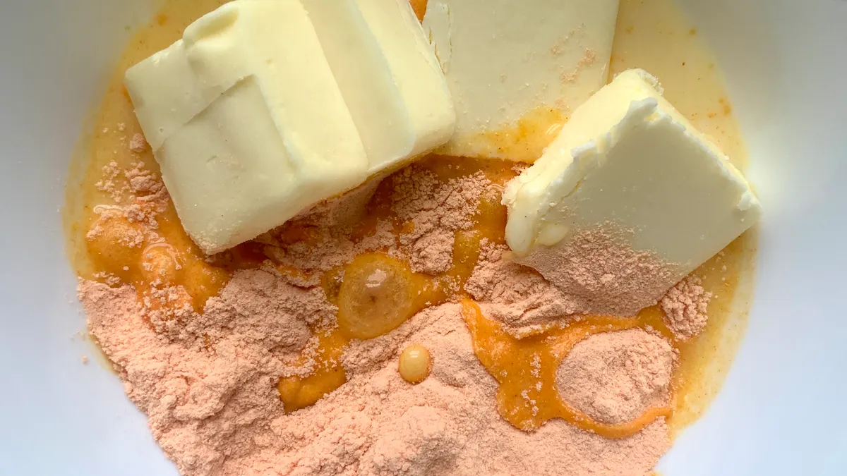 orange cheese powder with melting butter in a white bowl