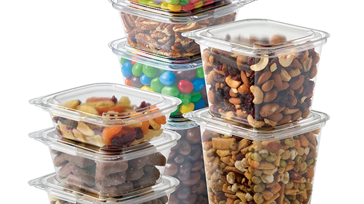 Stacked lear plastic containers of different sizes filled with nuts, candy and other snacks