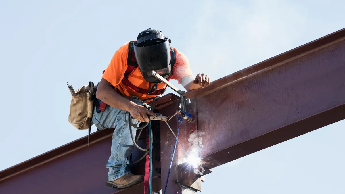 A construction worker welds a steel beam.