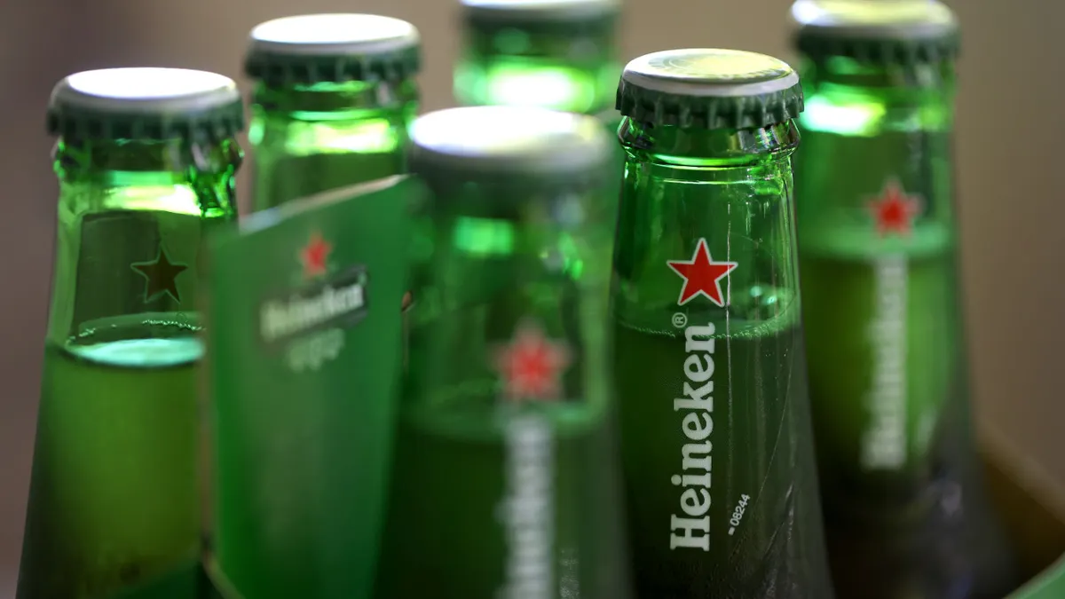 A six pack of Heineken bottles, with the focal point on one beer.